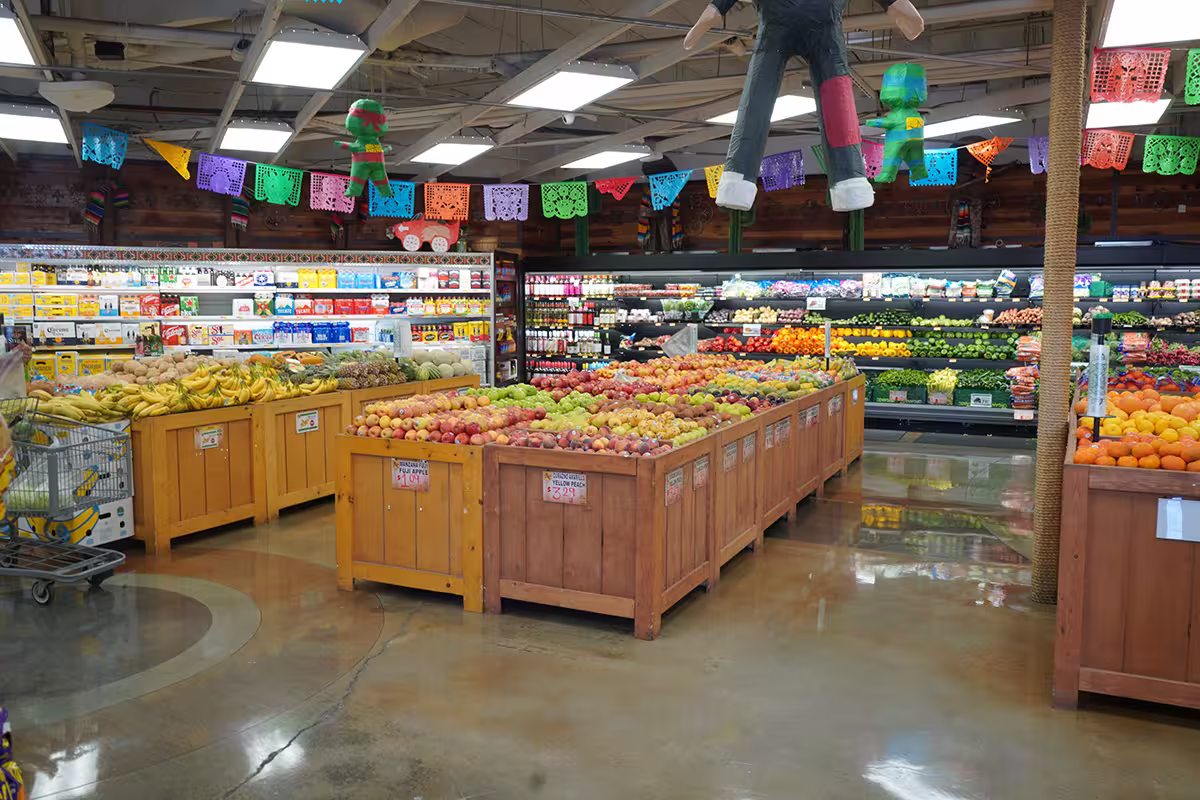 Produce section of a grocery store with fruit bins, hanging decorations, and ceiling lights